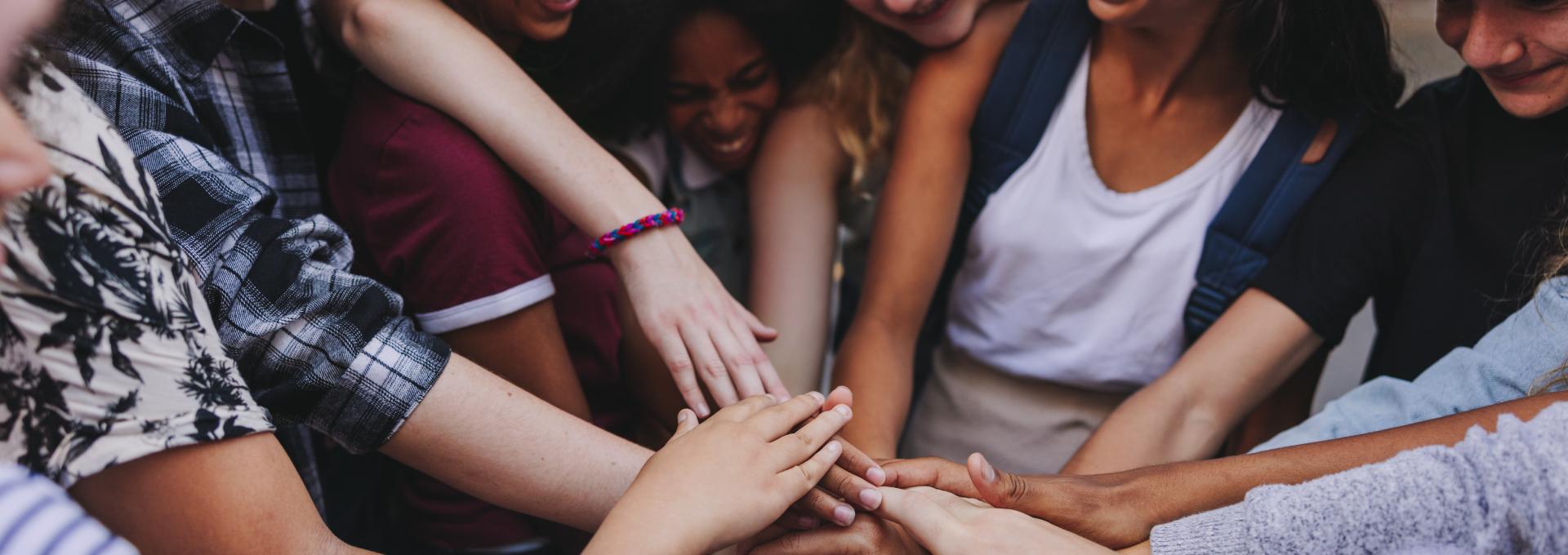 students from different cultures holding hands in a huddle